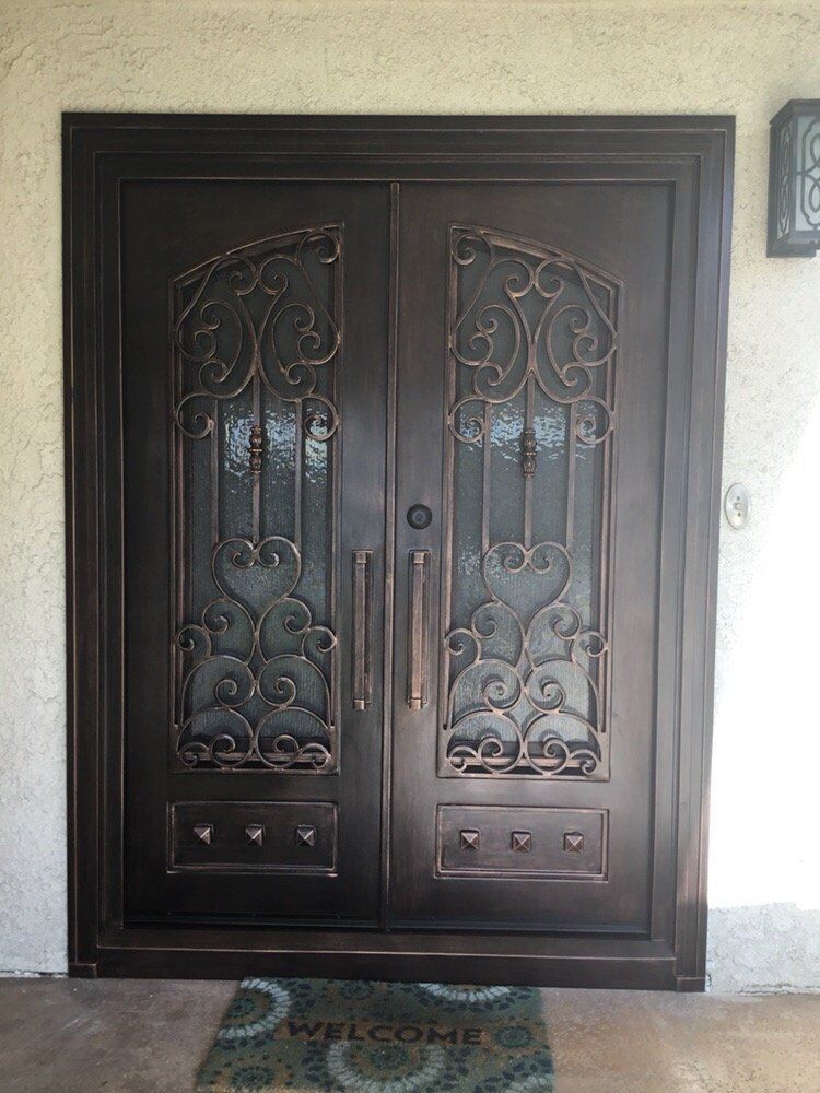 Bronze double front doors with decorative ironwork and glass panes.
