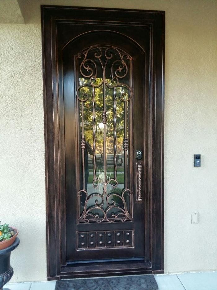 Ornate bronze front door with glass panel and decorative ironwork.